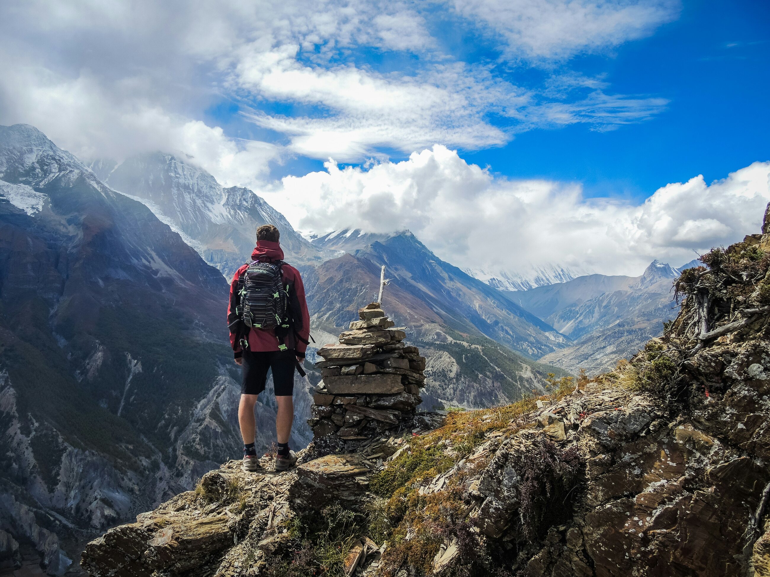 A hiker pausing at a stone cairn on a mountain ridge